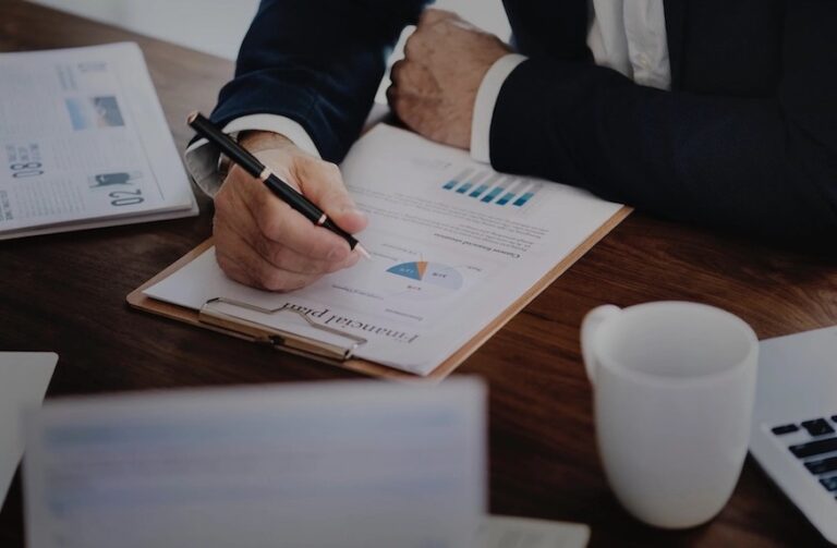 man writing on a paper with data and graphs