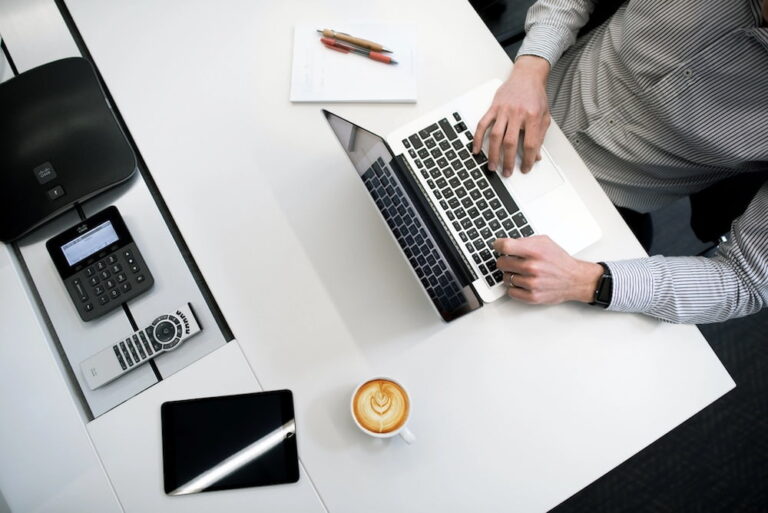 man sits at desk with laptop and coffee