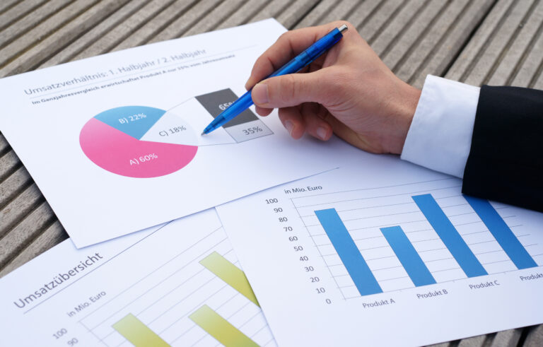 financial controller hand with pen examining businesss graphs