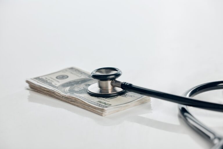 stack of cash with a stethoscope on top
