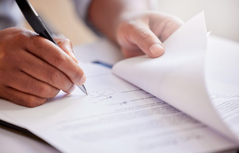 A close up image of an individual signing paperwork