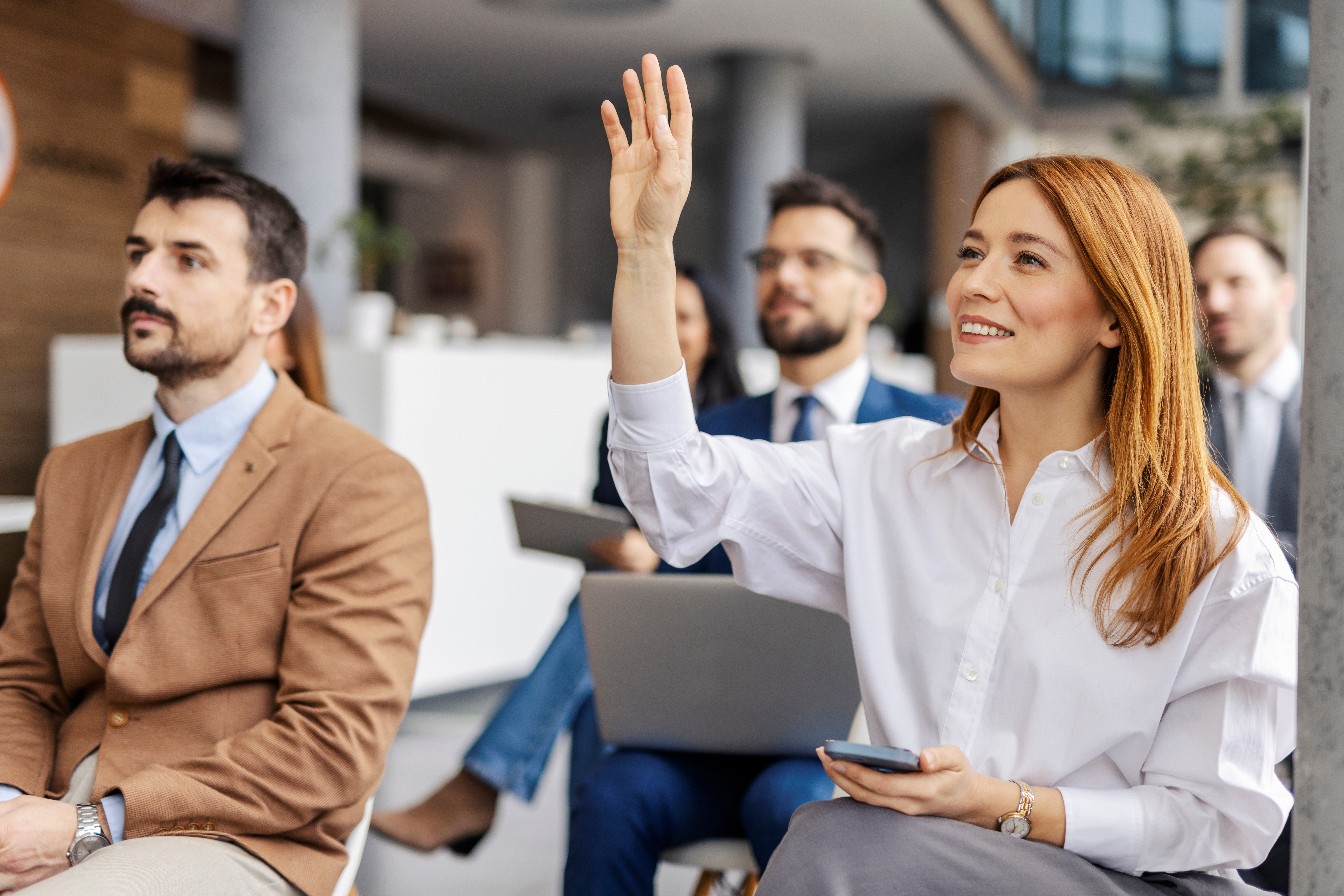 woman raising her hand to ask a question in a business meeting